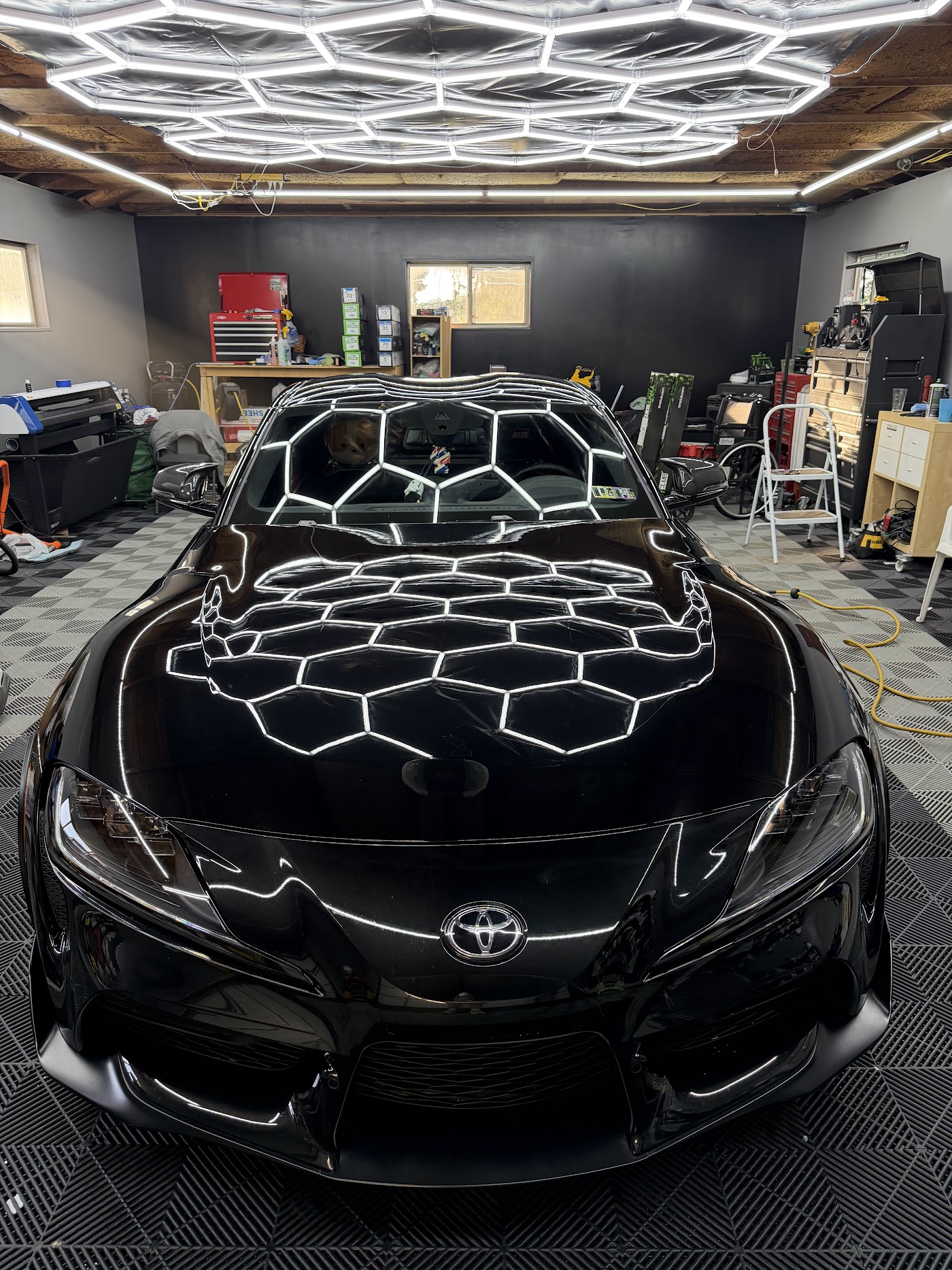 Black sedan with a deep mirror finish under hexagon studio lighting